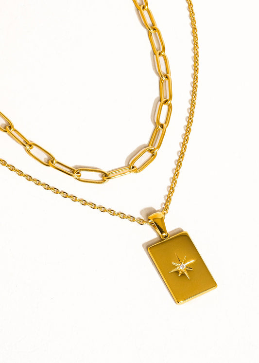 Gold chain necklace with a star pendant on a white background