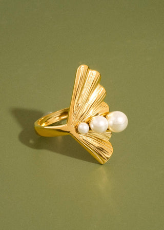 Gold ring with three pearls on a green background