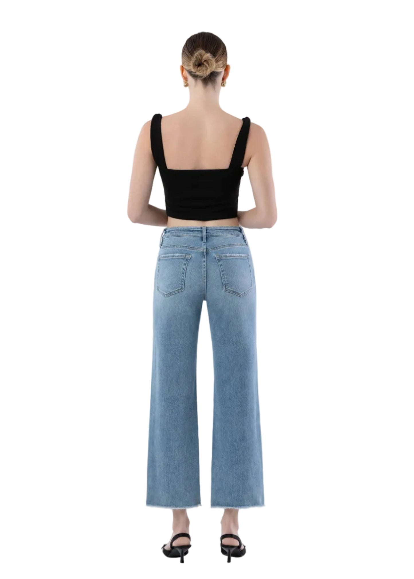 Person wearing a black crop top and light blue jeans on a white background