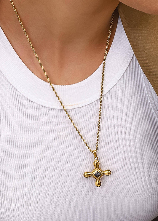 Gold necklace with a cross pendant on a white shirt