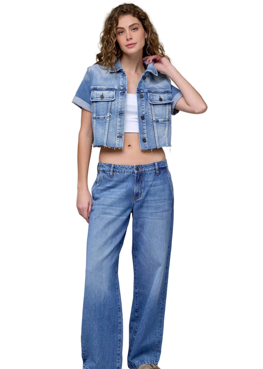 Woman wearing a denim jacket and jeans on a plain background