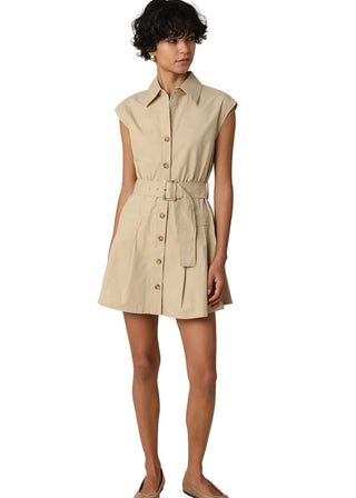 Woman wearing a beige dress with a belt against a plain background