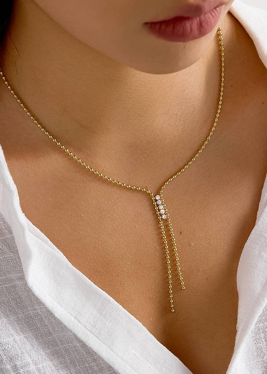 Gold necklace with a y-style design worn by a person in a white shirt.
