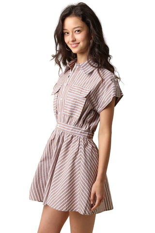 A woman modeling a short-sleeve collared mini dress with a vertical stripe pattern in brown and white, set against a plain beige studio background.