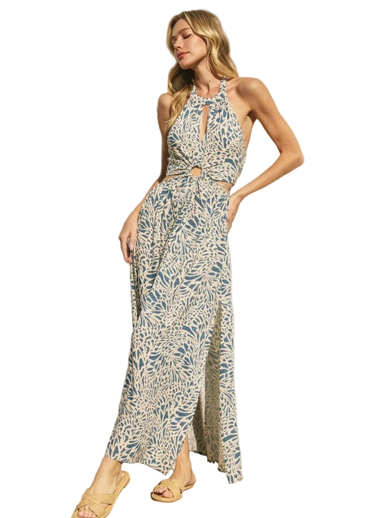 Woman wearing a blue patterned halter neck dress with cutouts on a white background