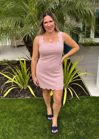 Woman in a pink dress standing outdoors with greenery in the background