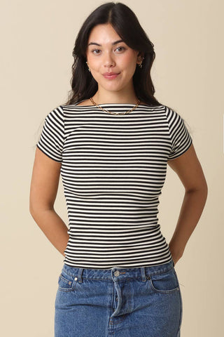 Woman wearing a navy and white striped shirt with blue jeans on a beige background