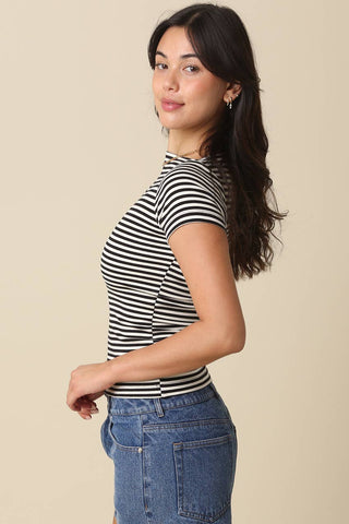 Woman wearing a navy and white striped top and blue jeans against a beige background