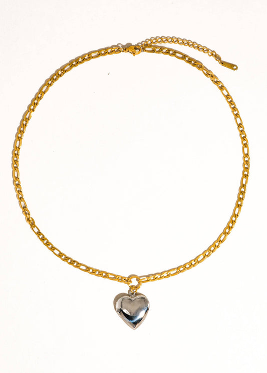 Gold chain bracelet with a silver heart charm on a white background