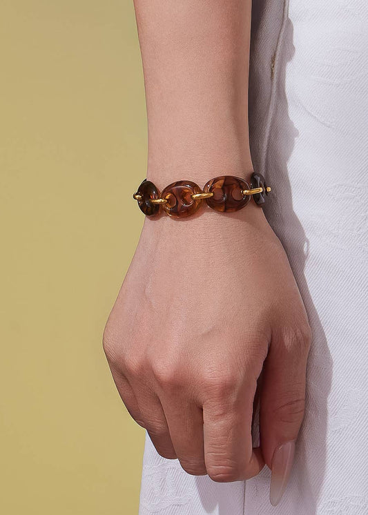 Hand wearing a tortoiseshell bracelet on a white and yellow background