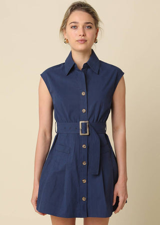 Woman wearing a blue sleeveless dress with a belt on a beige background