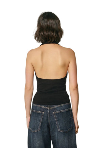 Person wearing a black halter top and blue jeans against a plain background