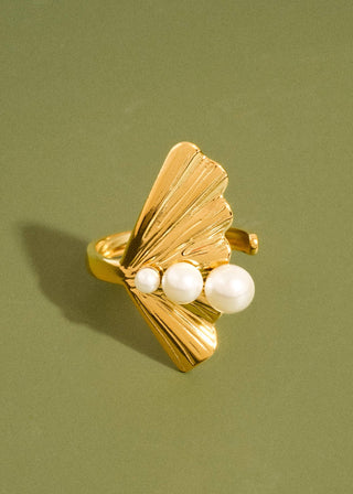 Gold ring with three pearls on a green background