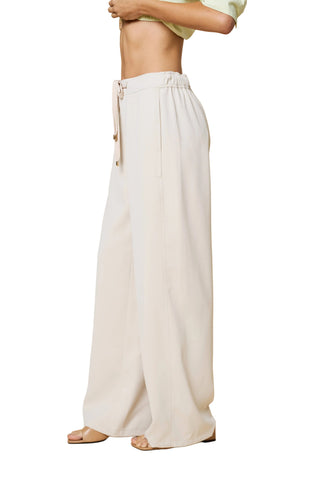 Person wearing white wide-leg pants on a beige background
