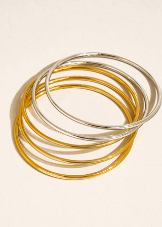 Set of gold and silver bangles on a beige background