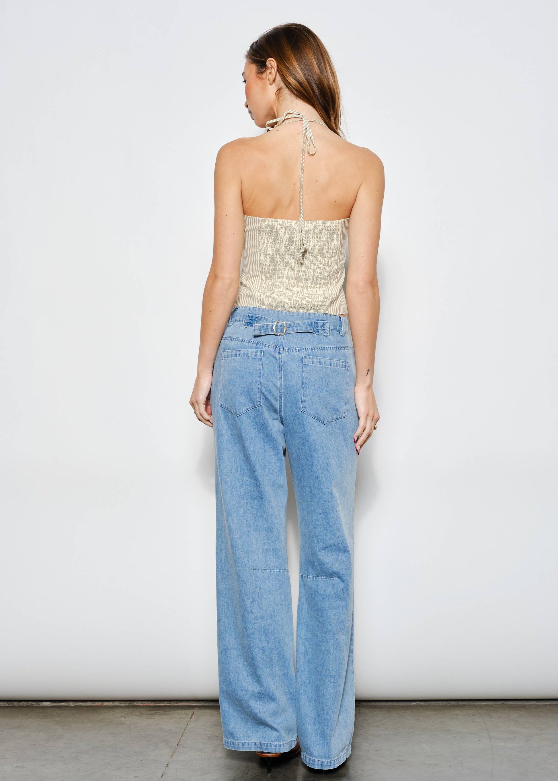 Woman wearing a strapless top and light blue jeans against a white background