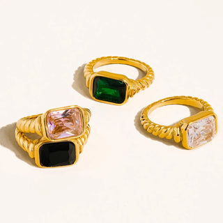 Three gold rings with gemstones on a white background