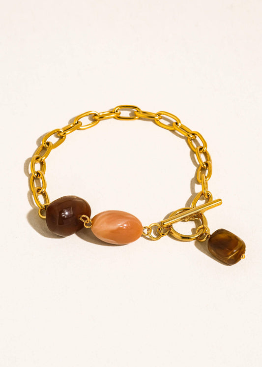 Gold chain bracelet with three colored beads on a white background