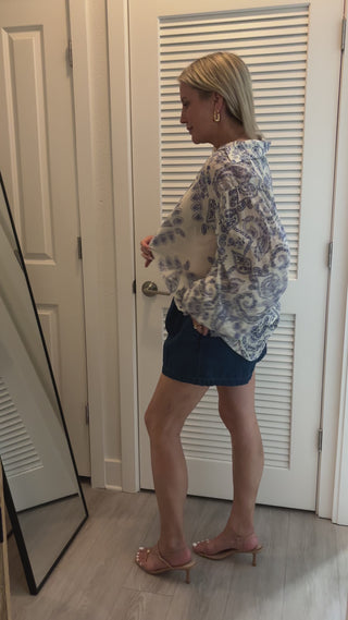 woman trying on blue and white blouse in mirror
