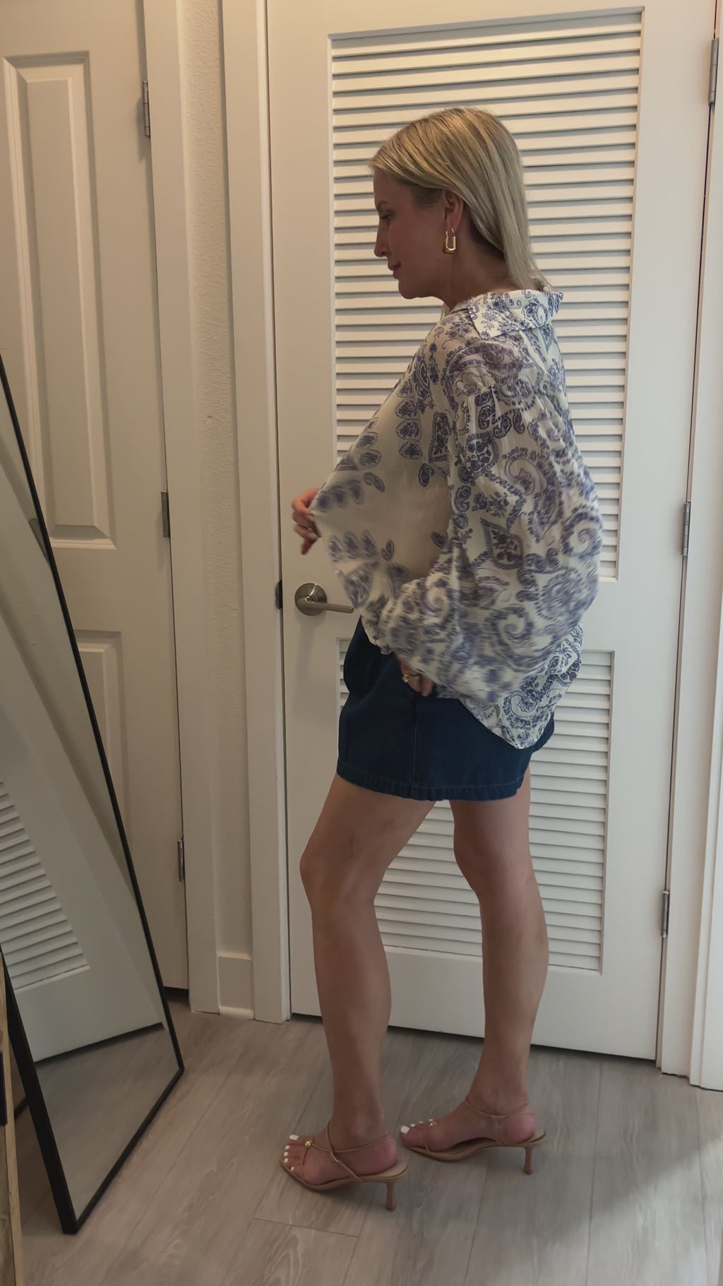 woman trying on blue and white blouse in mirror